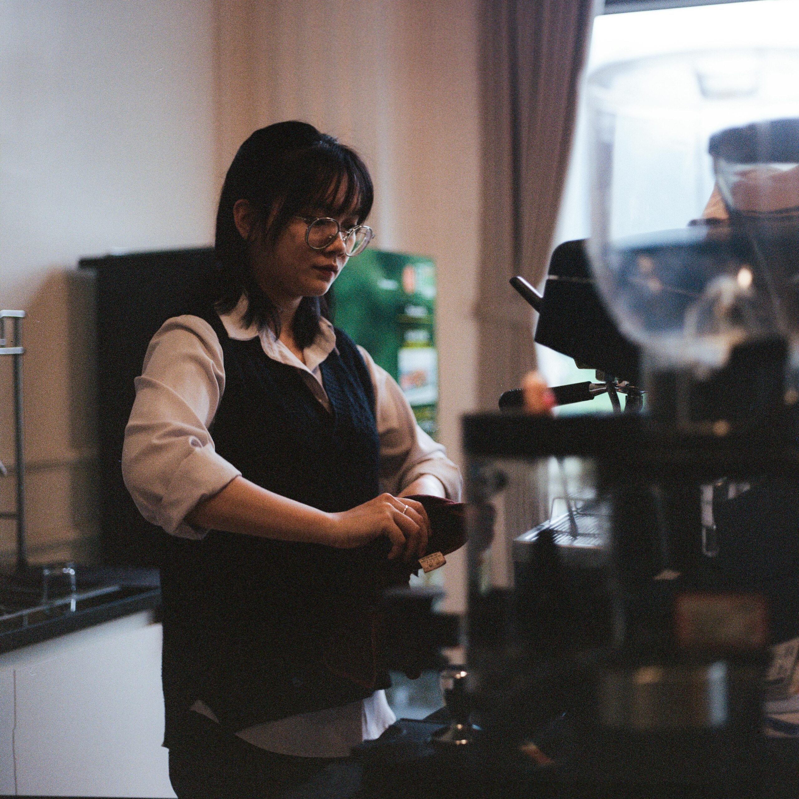 East Asian woman barista making coffee in a Vietnamese café, Hà Giang city.
